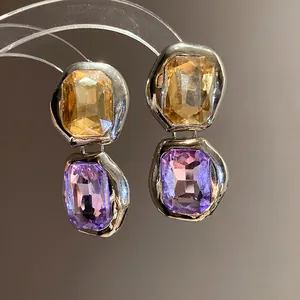 Macro detail of geometric square earrings with amber and purple gemstones in silver setting