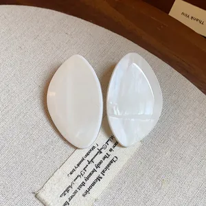Gros plan sur des boucles d'oreilles géométriques en résine blanche