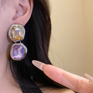 Close-up of elegant square rhinestone drop earrings with amber and purple stones