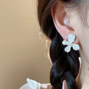 Dettaglio di un elegante orecchino a fiore in smalto bianco con una perla centrale