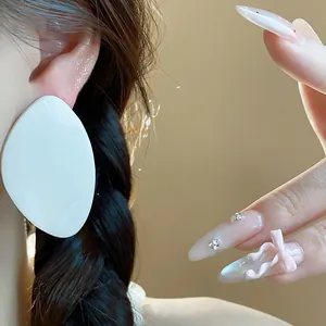 Gros plan d'une grande boucle d'oreille en résine blanche en forme de feuille stylée.
