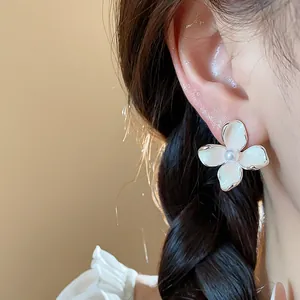 Dettaglio dell'orecchino a fiore smaltato bianco con perla indossato all'orecchio