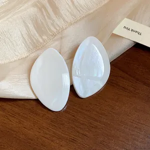 Gros plan sur des boucles d'oreilles géométriques en résine nacrée blanche