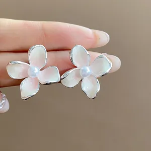 Primo piano di eleganti orecchini a lobo a fiore con petali in smalto e perla.