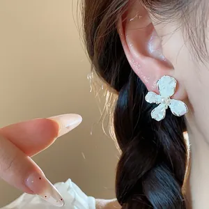 Dettaglio macro di un elegante orecchino a fiore bianco con perla sull'orecchio