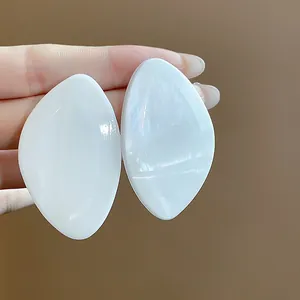 Vue détaillée de grandes boucles d'oreilles géométriques en résine blanche nacrée