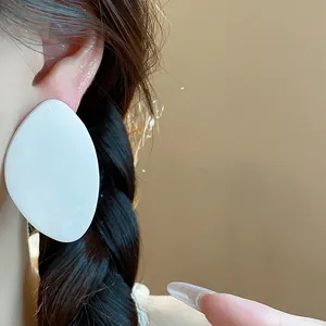 Vue rapprochée de la grande boucle d'oreille géométrique en résine blanche sur l'oreille.
