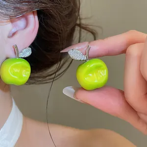 Detailed close-up of vibrant forest-style green apple stud earrings with crystal leaf