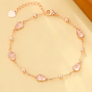 Detail van een elegante roségouden enkelband met roze kristallijne kalebasvormige bedels