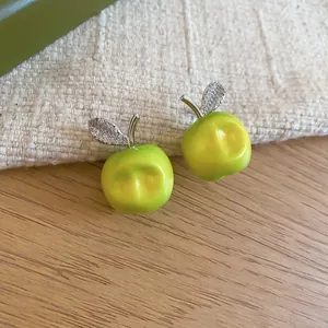 Macro view showing the fine details of green apple stud earrings with sparkly leaf accents