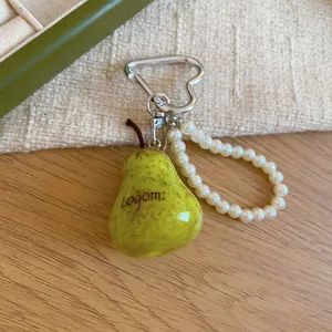Close-up of a pear-shaped charm with white pearl bead strap and silver heart carabiner