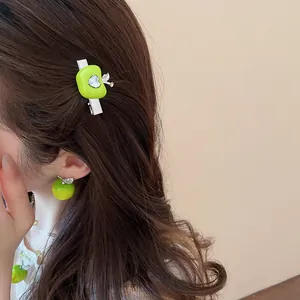Detailed view of forest style green apple hair clip and stud earring worn by a model