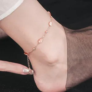 Close-up van een elegante roségouden enkelband met roze ijzige bedeltjes