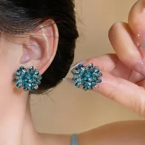 Close-up of teal glass beaded flower stud earrings showing the delicate beaded texture