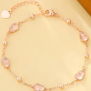 Gedetailleerd zicht op een elegante roségouden enkelband met roze kalebasbedels.