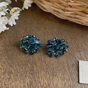 Close-up macro of deep blue glass beaded flower cluster earrings on rustic wood table