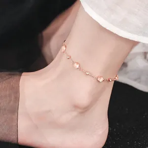 Detailopname van een elegante roségouden enkelband met roze hartvormige steentjes om de enkel