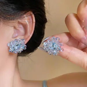 Macro detail of translucent glass beaded flower earrings in a soft light blue finish