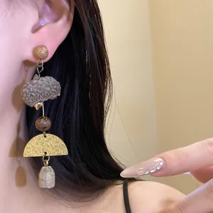 Close-up of retro forest style long earring with eucalyptus fruit and brass detail