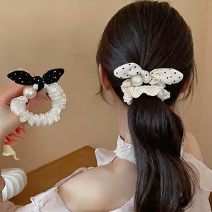Sweet polka dot bow scrunchie with pearl detail shown on a stylish woman's ponytail