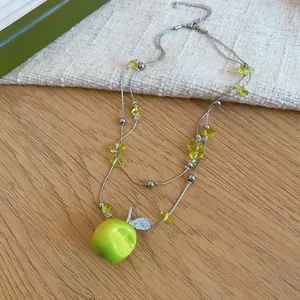 Detailed view of a green apple pendant necklace with clear beads and silver chain.