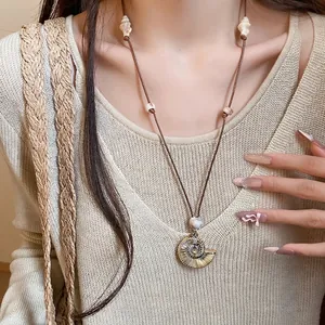 Elegant resort style necklace with shell pendant and ammonite detail on a brown cord