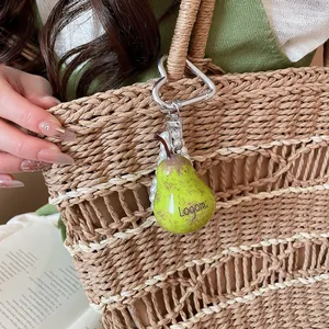Forest style green pear pendant charm with white pearls hanging on a woven straw bag detail
