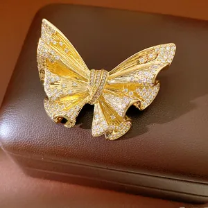 Detailed macro view of a sparkling 18K gold butterfly brooch with zircon stones on a box