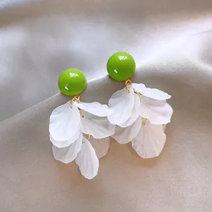 Primo piano di eleganti orecchini a nappa con fiori in acrilico verde e bianco su seta.