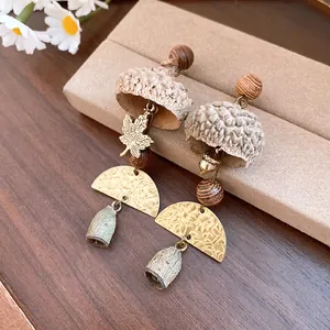 Detailed macro view of forest-style acorn drop earrings with textured gold accents