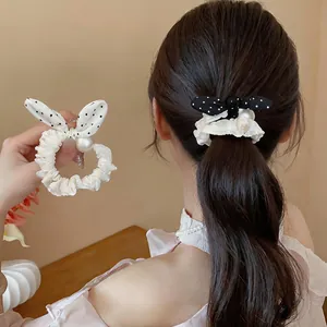Close-up of an elegant polka dot bow scrunchie with lace trim and decorative pearl accent