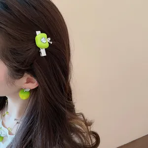Close-up view of a model wearing the fresh green apple hair clip and earring jewelry set