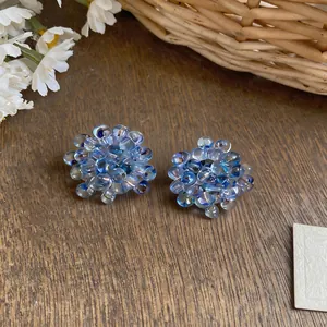 Detailed macro shot of blue glass beaded flower earrings placed on a rustic wooden texture