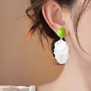 Primo piano di orecchini con nappe a petali di fiori in acrilico verde e bianco su modella