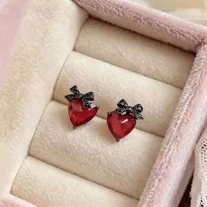 Elegant red heart stud earrings with black bow accents in a pink velvet jewelry box