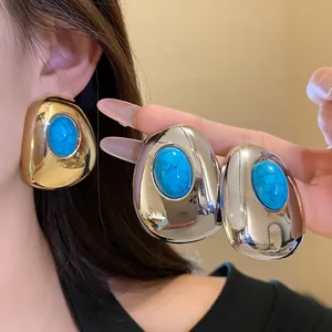 Close-up of vintage oval stud earrings with turquoise resin stones in gold and silver