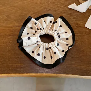 Detail view of the elegant polka dot ruffled hair scrunchie with black satin trim