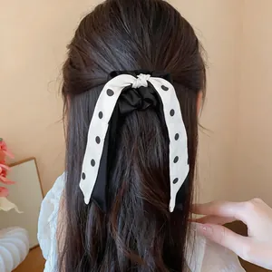 Close-up detail of a stylish black and white polka dot bow scrunchie on brown hair