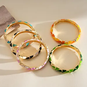 Primer plano de cinco brazaletes de metal esmaltado con coloridos diseños vibrantes.