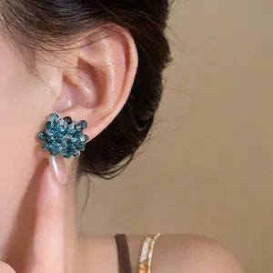 Close-up view of elegant blue glass beaded flower stud earrings worn by a model.