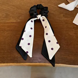 Detail of elegant black and white polka dot bow hair scrunchie on wooden surface