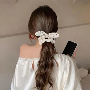 Close-up detail of a white polka dot bow hair scrunchie with lace trim and elegant pearl