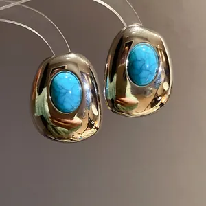 Detail view of vintage oval stud earrings with turquoise resin in silver finish.