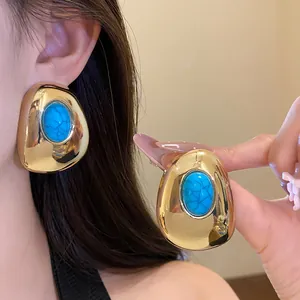 Close-up of vintage gold-tone oval stud earrings with turquoise resin stone