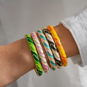 Primer plano de pulseras de esmalte metálico de colores con patrones retorcidos en la muñeca