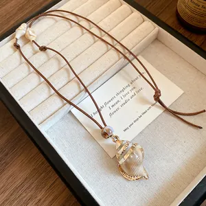 Detailed macro view of a beach-style seashell pendant necklace on a cream jewelry tray