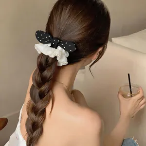 Close-up view of a sweet polka dot bow scrunchie with white pearl lace details on braided hair