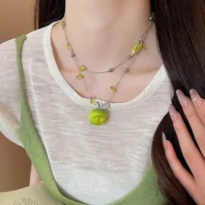 Detailed close-up of a forest-style green apple beaded pendant necklace on a model