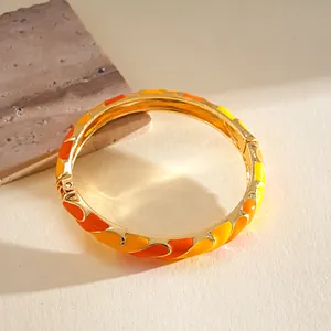 Vista detallada de los patrones de esmalte naranja y amarillo en brazalete dorado