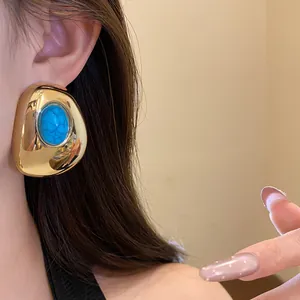 Detail shot of a vintage gold oval stud earring with a blue turquoise-style stone